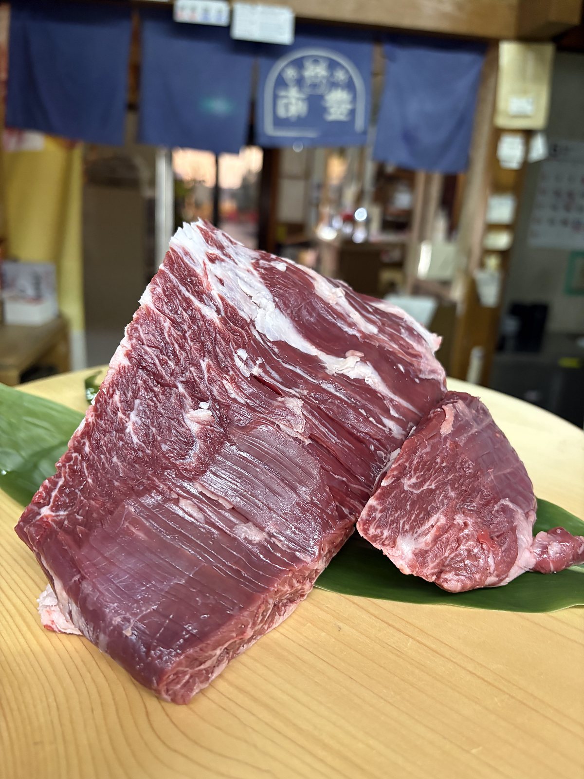 豊南焼肉が仕入れた近江牛の極上ハラミの塊。笹の葉を敷いた木のまな板の上に置いた赤身の肉塊