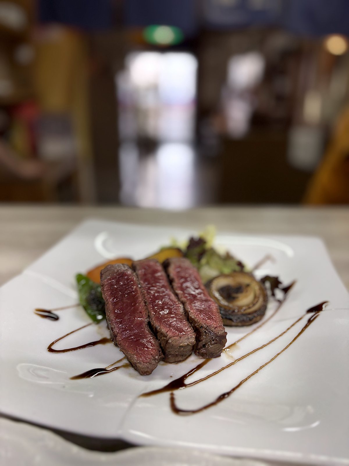 豊南焼肉の和牛ステーキ定食。白い角皿に厚切りの和牛ステーキを3切れ並べ、焼き野菜とソースを添えた一皿